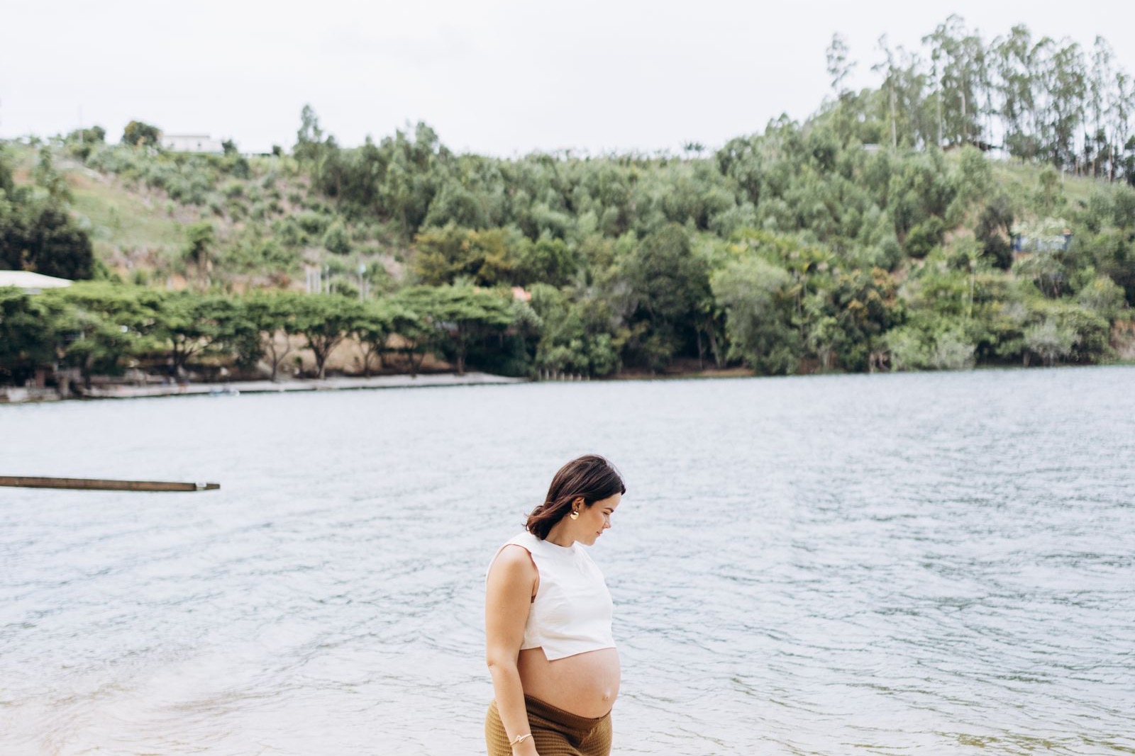 Pregnant woman walking outdoors beside a lake as part of daily prenatal activity